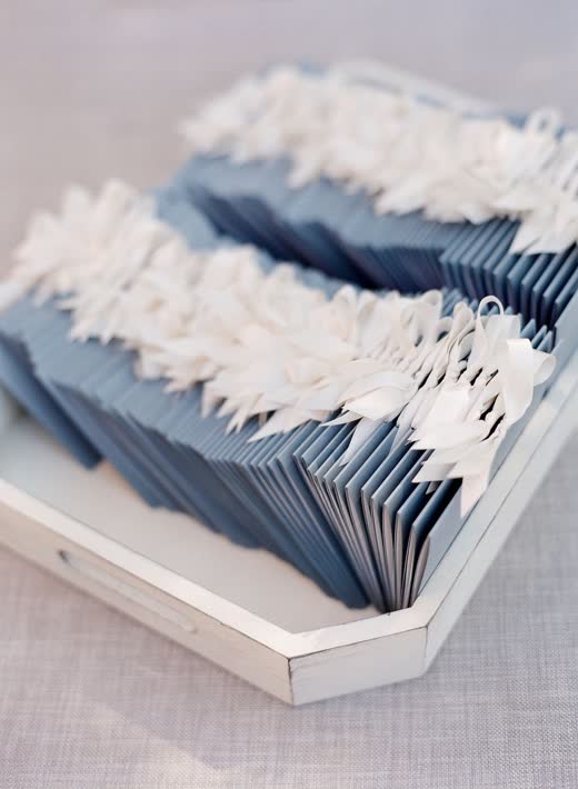 Pale blue escort cards fanned in a white tray