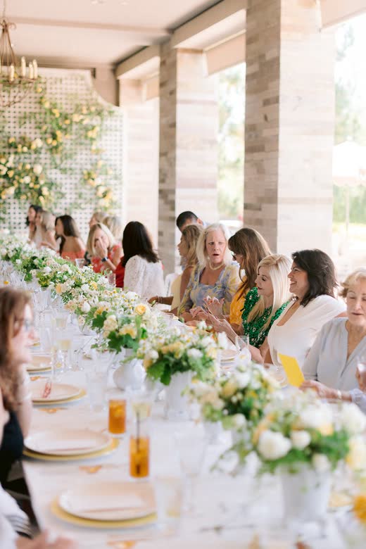 Guests at a long table dressed with white flowers